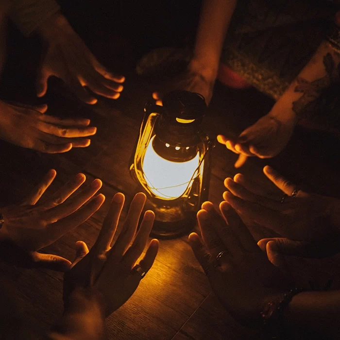 hands surrounding a lamp