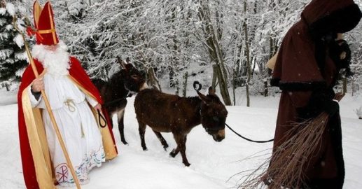 P’ere No’el & Le Pere Fouettard. Pere Noel or Santa with a red cloack with a hood trimmed in white fur walking in the snow